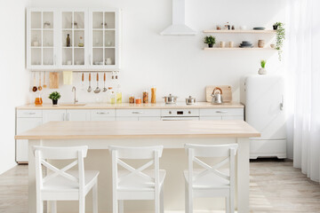 Style minimalism. Stylish kitchen in white and brown wood. Dining table, utensils and kitchenware on shelves