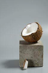 Creative conceptual still life with open coconut balance on concrete cube stand podium on gray...