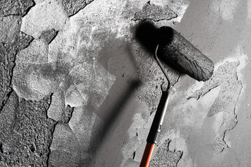 Paint roller on the black color wall background close up.