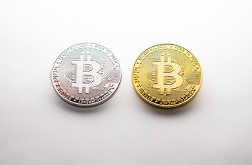 Two silver and gold Bitcoin coins on a white background, as a product shooting