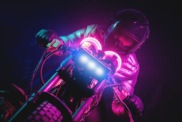 A futuristic motorbiker on the neon light motorcycle close up.