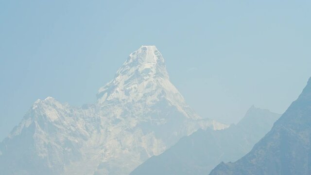 Stunning sky-high frozen snow peak of Ama Dablam Mountain towering in blue mist