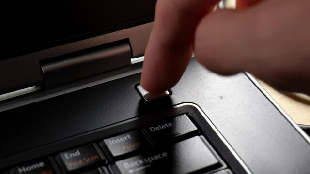 Anonymous man turning on a laptop, finger pressing the power button, switch object, hand detail, closeup, slow motion. Switching on an appliance, powering on a computer, technology usage concept