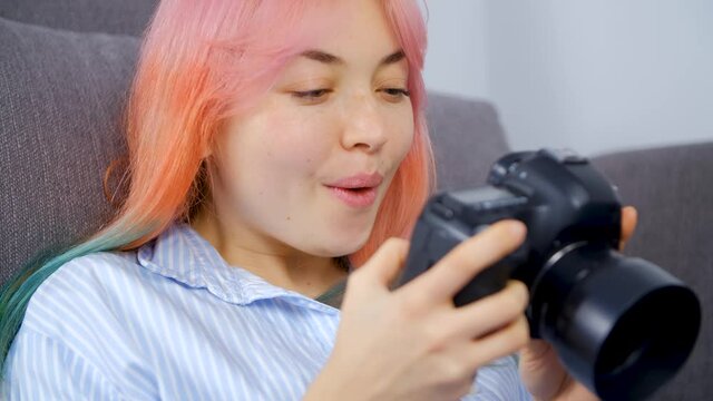 Excited photographer woman with colored hair browsing new photos on dslr camera. Creative professional girl with dyed hair viewing pictures on photocamera