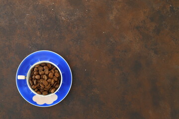 Close-up and top view of hot black coffee in blue coffee cup and roasted Thai coffee beans on wooden background.	
