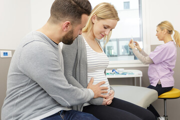 man supporting pregnant wife while nurse prepares injection