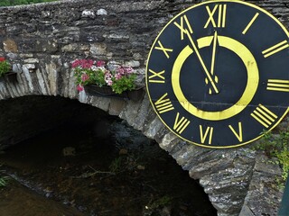 Brücke über den Idarbach mit alter Kirchturmuhr in Krummenau / Hunsrück