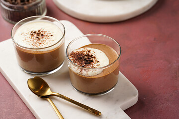 Italian chocolate and coffee mousse dessert semifreddo - half-frozen ice cream with whipped cream and cocoa powder in small glasses on burgundy surface