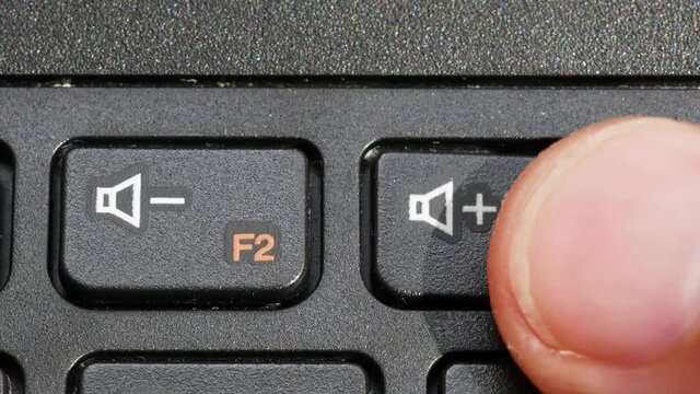 Man turning up the volume on a laptop keyboard, finger pressing the vol up speaker key vol+ button on a computer keyboard, object macro, detail, extreme closeup. Noise, loud music, audio controls