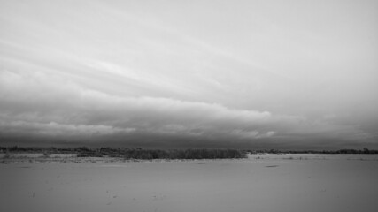 beautiful dramatic cloud coming up over snow covered field, black and white