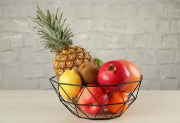 Fresh ripe fruits in metal bowl on wooden table