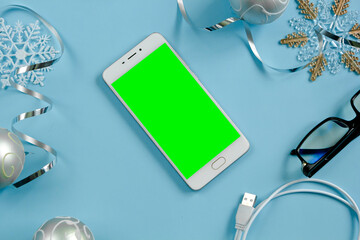 White phone with a green screen against the background of New Year's paraphernalia. New Year's greetings. Background. Copyspase
