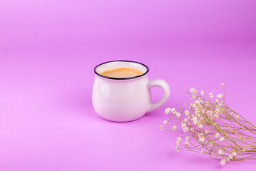 Cup of coffee with dry flowers branch on pink background. Morning minimal romantic concept.