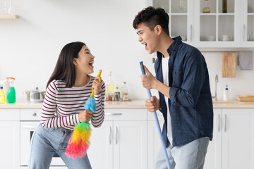 Funny asian man and woman singing songs while house-keeping
