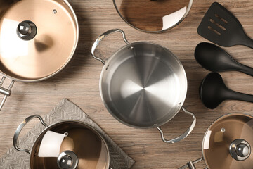 New cookware set and kitchen utensils on wooden table, flat lay