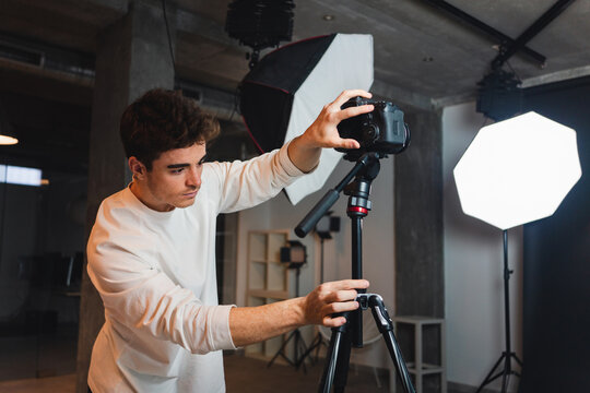 Man setting photo camera on tripod in studio