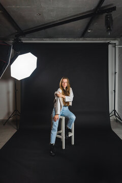Cheerful female sitting on chair in photo studio