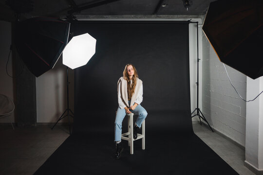 Cheerful female sitting on chair in photo studio