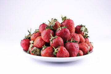 Fresh strawberry on white ceramic plate on white background.