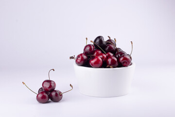 Sweet red cherry in white bowl on white background.