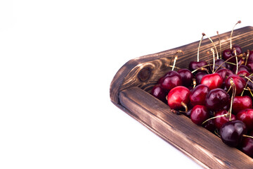 Sweet and ripe red cherry in wooden box on white background. close up image.