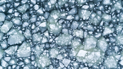 Aerial view over the surface of sea and cracked ice. Calm water with lots of small icebergs drifting around. Drone photography...
