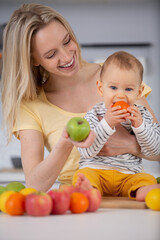 Fototapeta na wymiar cute baby boy sitting on table with fruits and vegetables