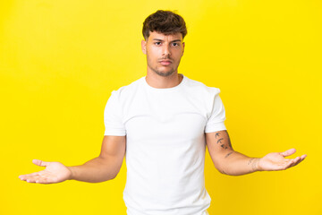 Young caucasian handsome man isolated on yellow background having doubts