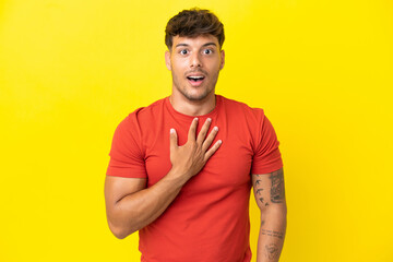 Young caucasian handsome man isolated on yellow background surprised and shocked while looking right