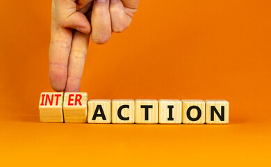 Action or interaction symbol. Businessman turns wooden cubes and changes the word action to interaction. Beautiful orange background, copy space. Business and action or interaction concept.