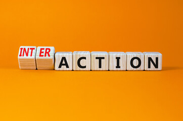 Action or interaction symbol. Turned wooden cubes and changed the word action to interaction. Beautiful orange background, copy space. Business and action or interaction concept.