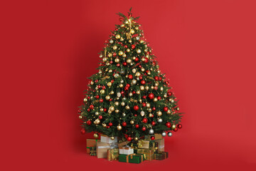 Beautifully decorated Christmas tree and many gift boxes on red background