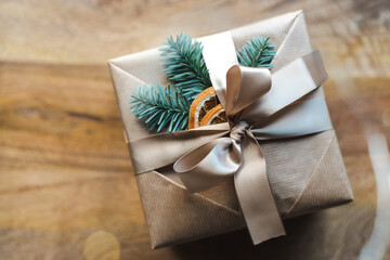 A beautifully wrapped Christmas present with natural decor on a wooden background.