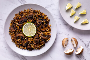 Mushroom pilau dish with rice and champignon fungi served with lime. Vegan cuisine.