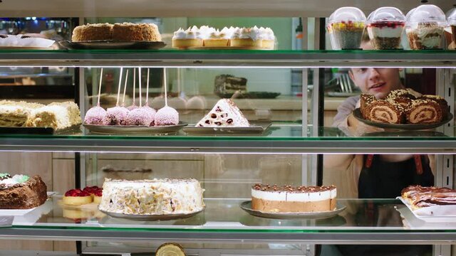 Concept of entrepreneur and small business food and restaurant young salesman open the showcase fridge and and add some fresh deserts in the showcase fridge