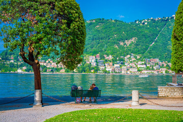 Fototapeta Romantic lakefront in Como harbour, tourist destination on Lake Como. The city contains numerous works of art, churches, gardens, museums, theatres, parks, and palaces obraz