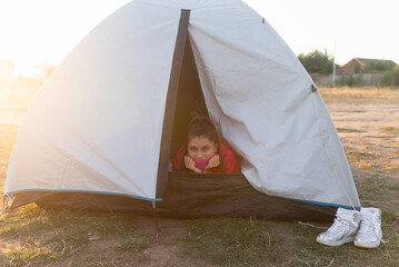 Young woman peeking out of the tent with only her head sticking out