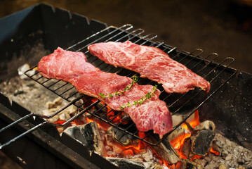 Two raw marbled beef steaks are grilled in the dark in the evening. Defocus