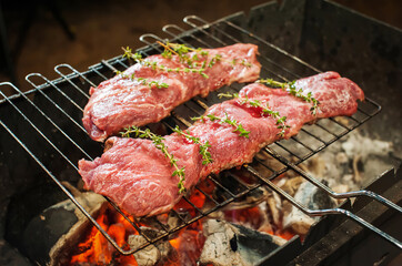 Grilling meat steaks in the evening in the dark close-up. Spices and herbs. Defocus