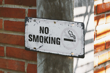 old rusty metal no smoking sign on brick wall