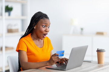 Online sale, remote shopping concept. Shocked black woman with credit card and laptop buying things...