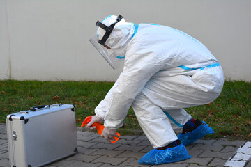 Fototapeta Mężczyzna w kombinezonie ochronnym podczas pandemii Covid-19 dezynfekuje sprzęt medyczny. obraz