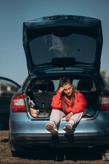 Attractive young woman resting in the trunk of a car