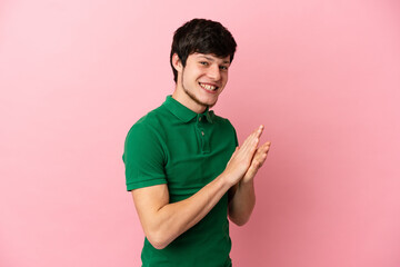 Young Russian man isolated on pink background applauding