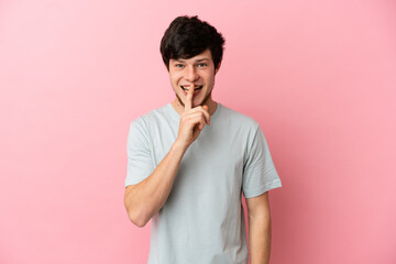 Young Russian man isolated on pink background showing a sign of silence gesture putting finger in mouth