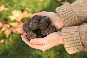 Woman holding fresh truffles in hands outdoors, closeup