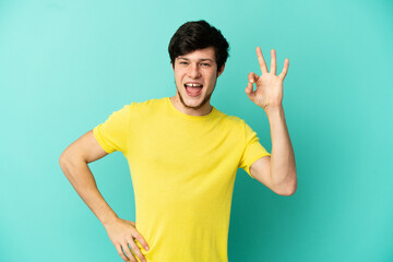 Young Russian man isolated on blue background showing ok sign with fingers