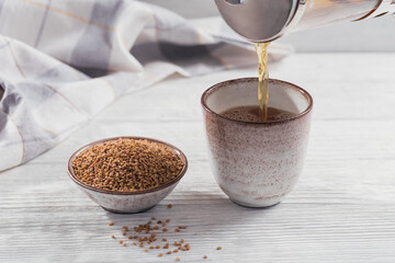 Bowl of fenugreek seeds and Egyptian fenugreek yellow tea or Methi Dana drink on white wooden...