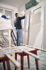 Young adult man painting on a DIY budget renovation of his new home apartment.