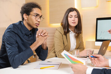 Going over details. Group of young confident business people discussing something while spending time in the office. Male office worker looking at colleagues while discussing something